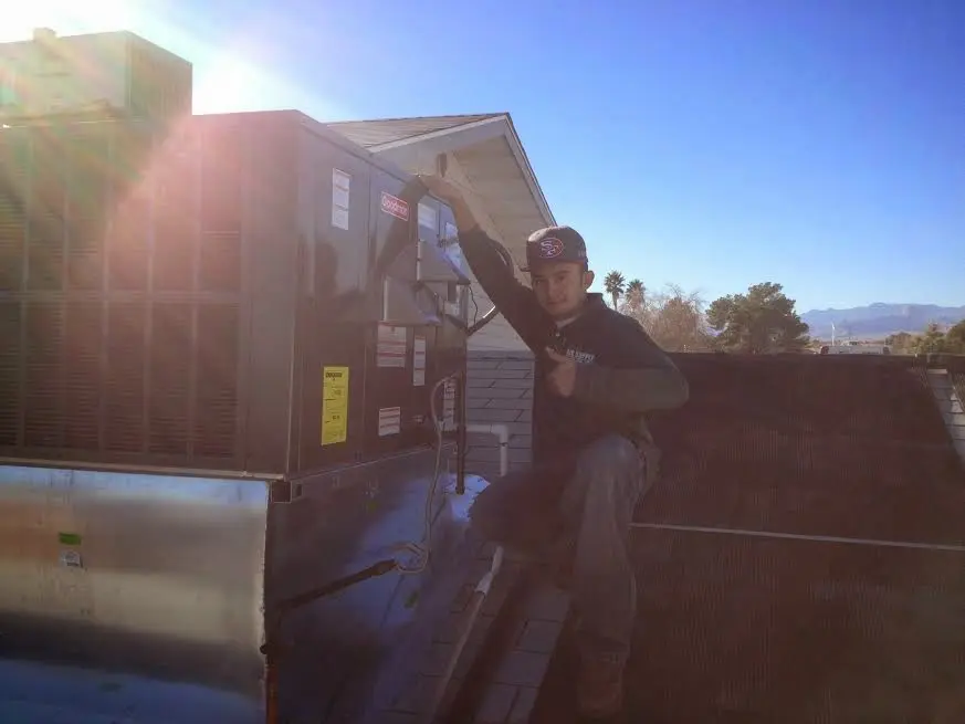 HVAC technician performing AC Tune-Up on a rooftop unit in Huntington